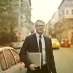 Man in a suit carrying a laptop on a busy city street